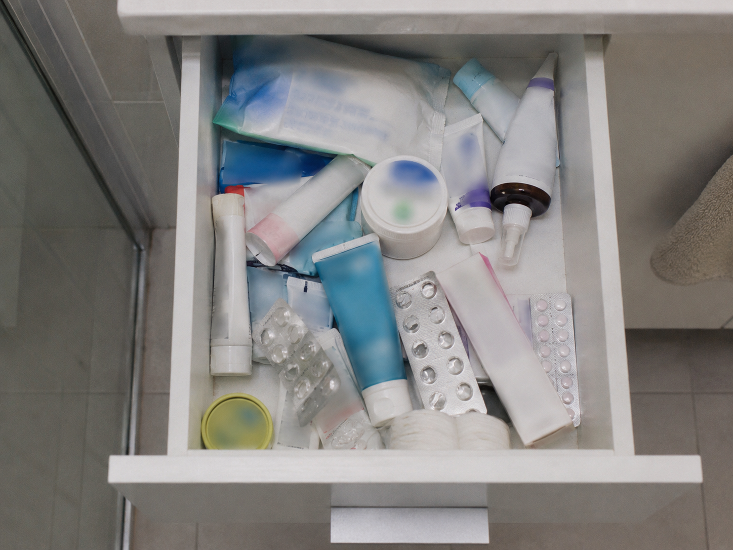 Badezimmerschublade mit halb aufgebrauchten Salben, Tropfen und Cremes, die nicht geholfen haben
